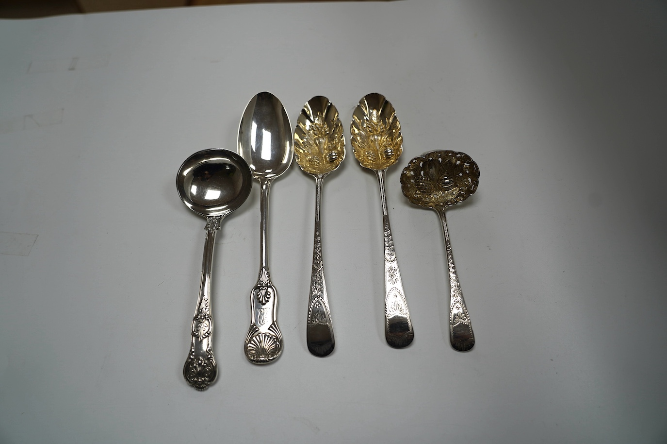 A pair of George III silver berry spoons, London, 1804, together with three other spoons, including a Georgian Scottish table spoon and a George III silver berry sifter spoon, Eley, Fearn & Chawner, London, 1809, 10.6oz.